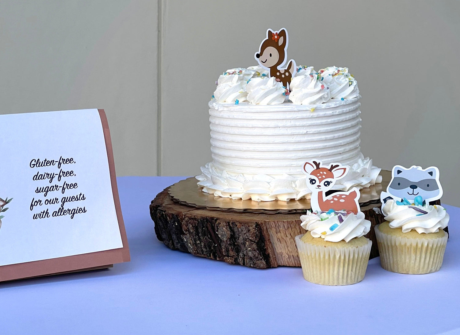 Woodland-themed cake and cupcakes with a sign on a table